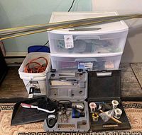 Front view of entire lot showing storage cart, bucket of wires, metal rods on top, several tool cases, cords, and tools.