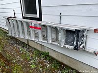 Side view of aluminum extension ladder leaning against exterior wall