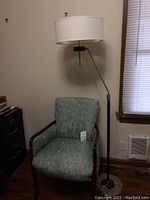 Floor lamp and upholstered armchair positioned against wall near window, showing overall items in the lot.