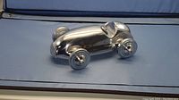 Side view of the shiny aluminum model car showing the aerodynamic shape and front wheels.