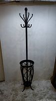 Full view of standing coat rack showing top hooks and umbrella holder at base