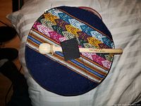 Drum with colorful woven fabric cover and wooden mallet on top