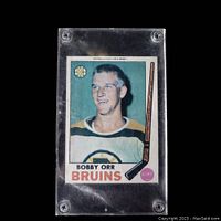 Front view of vintage Bobby Orr hockey card in a clear plexiglass case showing the player photo, name, team logo, and text details.