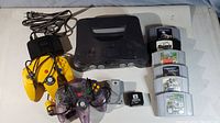 Overhead view of console, controllers, memory modules and game cartridges on gray mat
