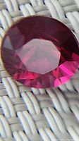 Close-up front view of a deep red faceted round ruby gemstone.
