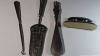 Set of three vintage sterling silver items: serving spatula, shoehorn, letter opener, all showing ornate handles and vintage patina.