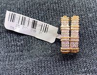 Close-up image showing the earrings from the side, highlighting the diamond pave setting and attached price tag with barcode and 'Made in Italy' marking.