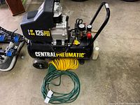 Front-right angled view of compressor with yellow coiled hose and green hose at base
