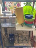 Photo of plastic storage containers, colorful Tupperware bowls, vintage yellow Tupperware container, glass vases, and plastic platters arranged on shelves