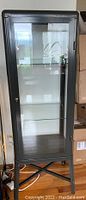 Front view of closed gray metal frame cabinet with glass door, showing overall shape and size.