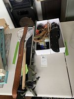 Photo of Primos Hunting Trigger Stick monopod, vintage leather whip, fishing net, knives in sheaths inside a box