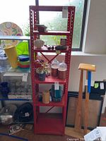 Red metal rack displayed with various household items on shelves, showing overall appearance and condition.
