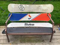 Front view of the snowboard bench showing four different snowboards used for seat and backrest on metal frame.