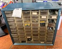 Front view of blue metal Akro-Mils box with 56 clear drawers containing assorted hardware