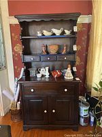 Front view of dark wood buffet with shelves, drawers, and cabinet doors, showing some decorative items on shelves