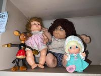 Photo showing three items: Wooden Minnie Mouse statue, Cabbage Patch doll in pink dress, and a Precious Moments doll with bonnet.