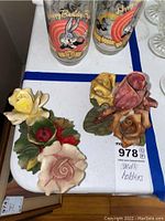 Two Capodimonte porcelain candle holders with floral designs and a porcelain flower decoration with old wax residue and a chipped area visible.