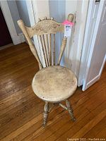 Front view of the wooden clawfoot piano chair showing carved backrest and round seat.