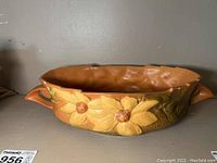 Full side view of the Roseville planter showing yellow flower decorations and matte brown interior.