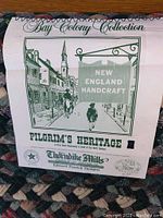Close-up of the rug's inner label illustrating the Bay Colony Collection and New England Handcraft theme with Pilgrim's Heritage logo.