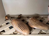 Pair of antique wooden and metal shoe stretchers shown side by side on a slatted surface.
