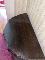 Top view of the wooden side table showing chipped veneer, scratches, loose top surface and worn dark wood finish.