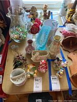 Wide view of all items on a wooden table showing the pitcher with marbles, multiple vases, and figurines