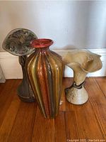 Three vases arranged on wooden floor showing different shapes and colors