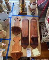 Four wooden wall sconces arranged on a table, showing different shapes and sizes with natural wood finish.