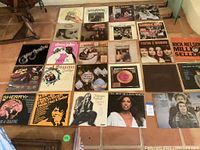 Photo showing a collection of vinyl album covers arranged on the floor featuring artists such as The Four Seasons, Elton John, Mamas and the Papas, Carly Simon, Simon and Garfunkel, and Rick Nelson.