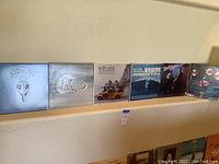 Six album covers in a row against a wall