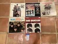 Photo showing six Beatles vinyl albums arranged on tiled floor, including Yesterday and Today, Something New, Beatles 65, The Early Beatles, and A Hard Day's Night soundtrack.