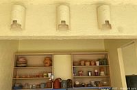 Wide view of shelving unit holding multiple gardening pots, watering cans, and containers arranged neatly on shelves.