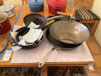 Overview of cookware set with pans, wok, cast iron press, and waffle maker on table.