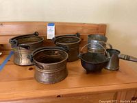 Full view of the six kitchen items including three copper pots, sifter, butter pourer, and small fire pot.