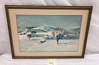Full view of framed watercolor painting showing winter landscape with snow, trees, and houses in a rolling hill setting.