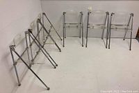 Six folding chairs arranged folded and open to show overall set and count