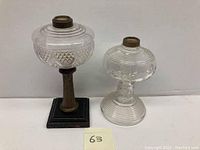 Two antique whale oil lamps showing pressed glass globes and different bases.