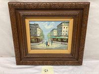 Full view of framed oil painting showing street scene with pedestrians and buildings.
