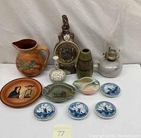 Full view of lot showing all items including pitcher, decanter, vases, oil lamp, large plate, small plates, and ashtray