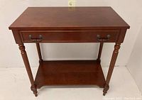 Front view of vintage mahogany console table showing drawer and turned legs.
