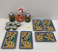 Full view of the Geisha figurine, sake bottles, cups, and rectangular plates arranged together