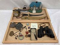 Full tray showing doorstop, dagger with sheath, stapler, vintage desk clock and other small collectibles arranged on wooden tray.