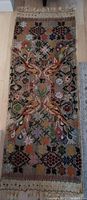 Full view of vintage Indian embroidered tapestry showing floral and peacock design, long rectangular shape, fringed ends