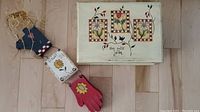 Photo of garden theme wall décor showing three connected wooden pieces with a red glove, sunflower panel, and blue flower pot with straw loop.