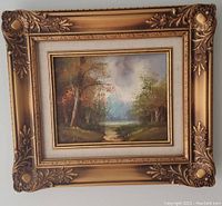 Full view of oil on canvas landscape painting in gold-colored ornate frame.