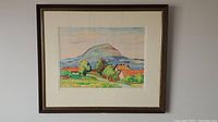 Framed pastel landscape artwork showing houses with orange roofs, trees, a pathway, and a mountain background.