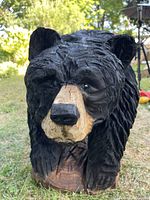Front view of black-painted wooden bear cub carving showing head and chest