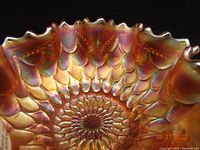 Close-up view of the bowl's intricate overlapping fish scale pattern and sawtooth rim with iridescent carnival glass finish.