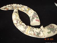 Pair of elaborately carved resin tusks with painted Chinese figures and motifs on black background.